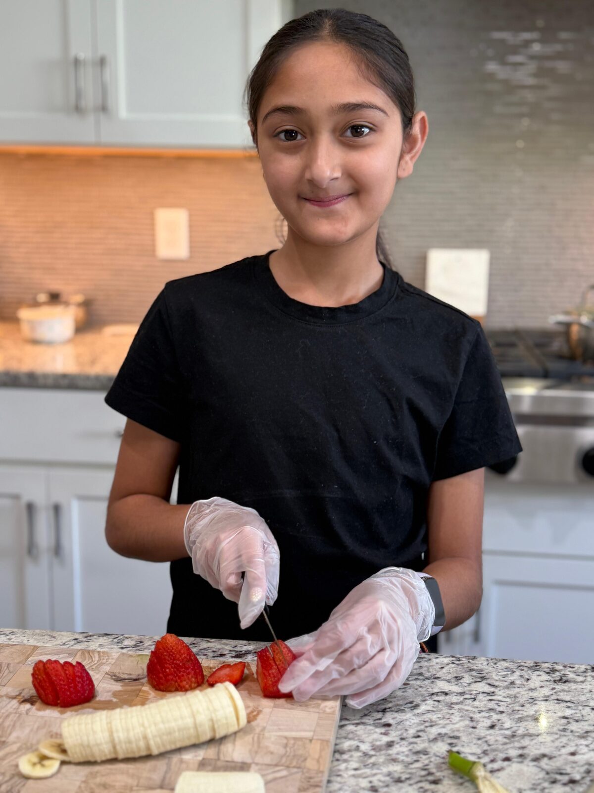 Arianna smiling while cutting fresh strawberries and banana for açaí bowls